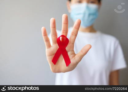 Hand holding Red Ribbon for December World Aids Day (acquired immune deficiency syndrome), multiple myeloma Cancer Awareness month and National Red ribbon week. Healthcare and world cancer day concept