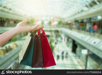 hand holding shopping bags in big shopping mall. hand holding bags