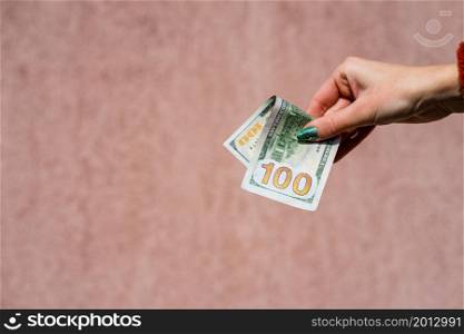 Hand holding showing dollars money and giving or receiving money like tips, salary. 100 USD banknotes, American Dollars currency isolated with copy space.