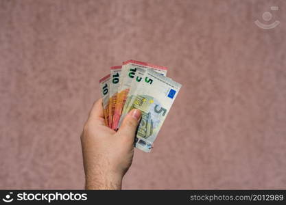 Hand holding showing euro money and giving or receiving money like tips, salary. 5 and 10 EURO banknotes EUR currency isolated. Concept of rich business people, saving or spending money.