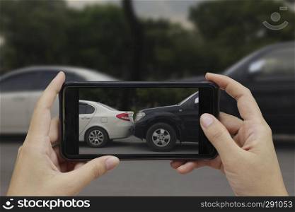 Hand holding smart phone take a photo at The scene of a car crash, car accident for insurance.