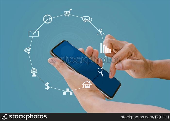 Hand holding smart phone with blurred social media and technology icons on blue color background.