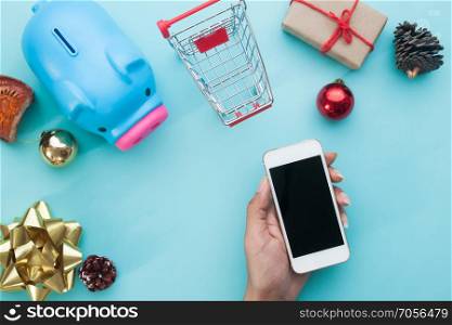 Hand holding smartphone with Christmas decorations. Christmas mock up template for online shopping concept. View from above