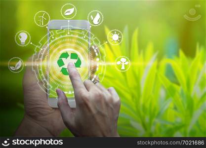 Hand holding smartphone with environment Icons over the Network connection on nature background, Technology ecology concept.