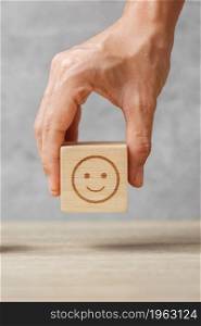 hand holding smile face block. Customer choose Emoticon for user reviews. Service rating, ranking, customer review, satisfaction, mood, mental health and feedback concept