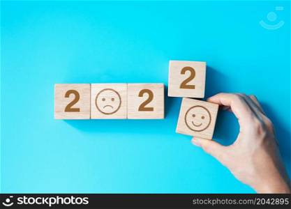 hand holding Smile face block with 2022 text on blue background. Satisfaction, feedback, Review and New Year concepts