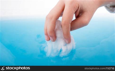 Hand holding some cotton in blue water