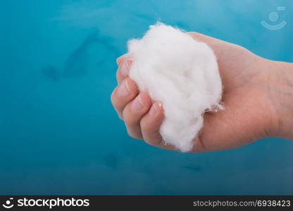 Hand holding some cotton in hand over blue water
