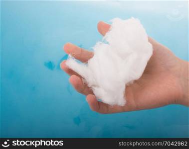 Hand holding some cotton in hand over blue water