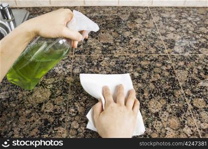 Hand holding spray bottle to clean stone kitchen countertops