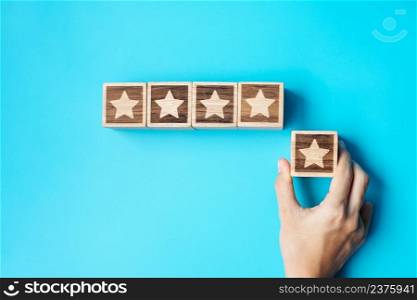 hand holding Star block on blue background. Customer choose rating for user reviews. Service rating, ranking, customer review, satisfaction, evaluation and feedback concept
