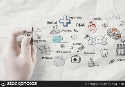 hand holding stethoscope shows medical icons on crumpled paper as concept 