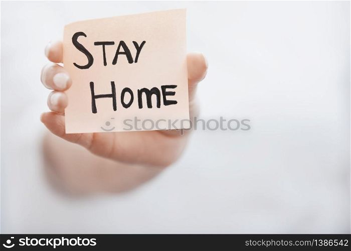 Hand holding sticky note with Stay Home text