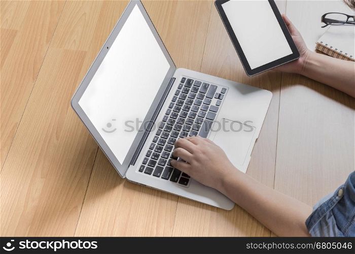 hand holding tablet with computer notebook on office desk
