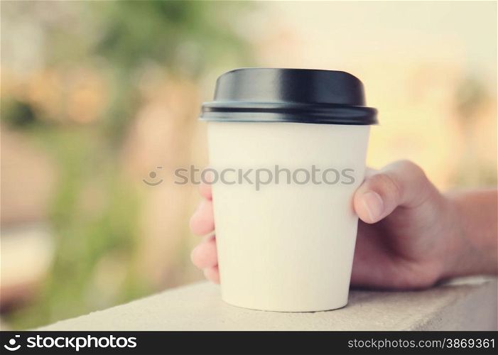 Hand holding take away coffee cup with retro filter effect