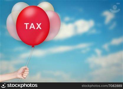 Hand Holding tax Balloon with sky blurred background