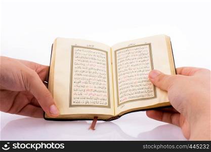 Hand holding The Holy Quran on a white background