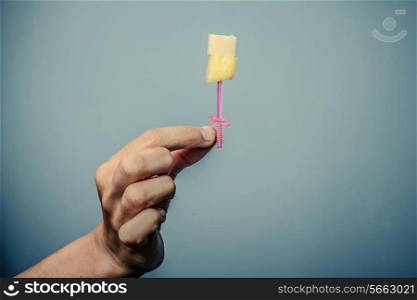 Hand holding toothpick with pineapple