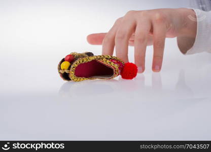 Hand holding traditional Turkish handmade shoes on white background