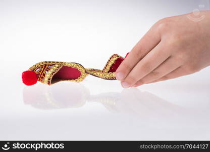 Hand holding traditional Turkish handmade shoes on white background