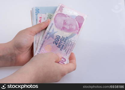 Hand holding Turksh Lira banknotes on white background