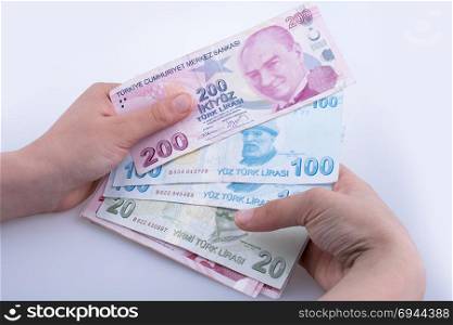 Hand holding Turksh Lira banknotes on white background