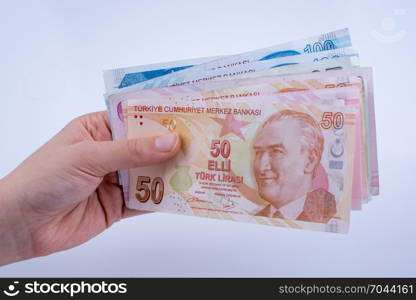 Hand holding Turksh Lira banknotes on white background