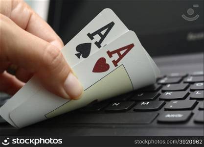 hand holding two aces over the laptop keyboard