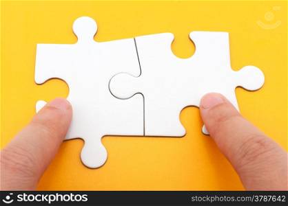 Hand holding two matching white paper jigsaw puzzles
