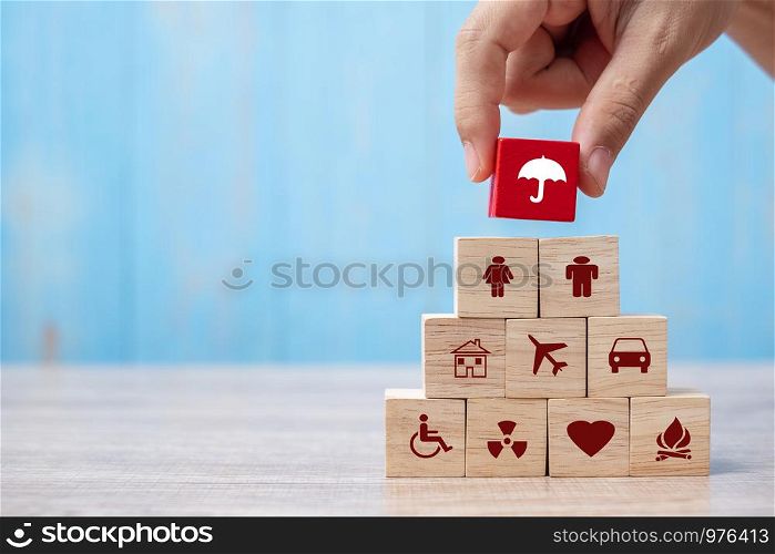 Hand holding umbrella wood block cover Insurance icon. healthcare medical, life, car, home, travel insurance concept