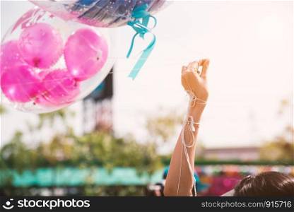 Hand holding up rope of greeting balloon for special event or birthday party. Happiness and celebration party concept. Friendship congratulation and happy people theme. Graduated event theme
