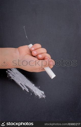Hand holding white chalk and black board