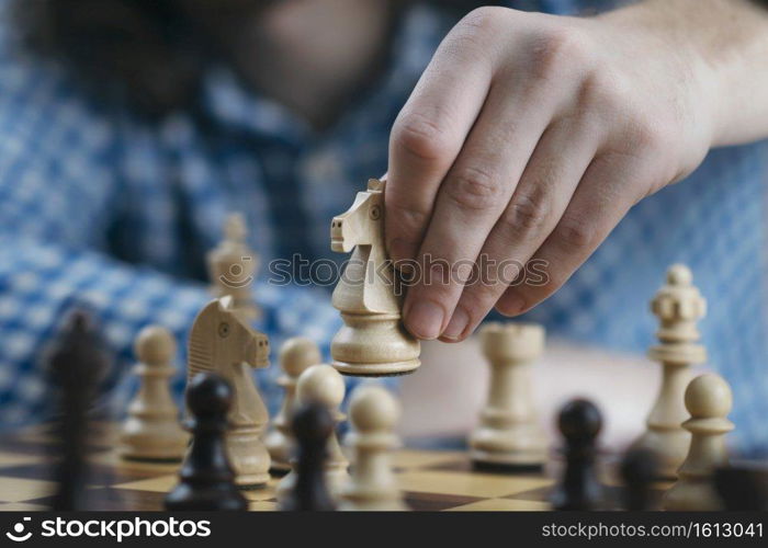 Hand holding white knight chess piece and playing chess game. Developing strategy for win and success.. Hand of Chess Player Moving the Chess Piece