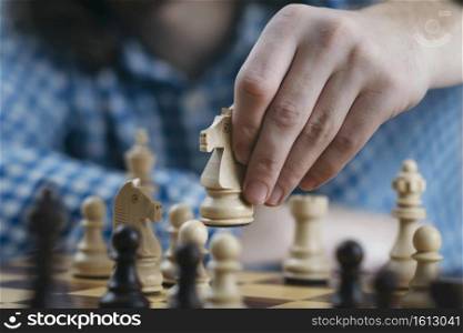 Hand holding white knight chess piece and playing chess game. Developing strategy for win and success.. Hand of Chess Player Moving the Chess Piece