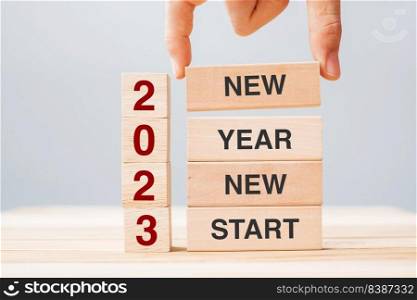 hand holding wooden block with text 2023 NEW YEAR NEW START on table background. Resolution, strategy, solution, business and holiday concepts