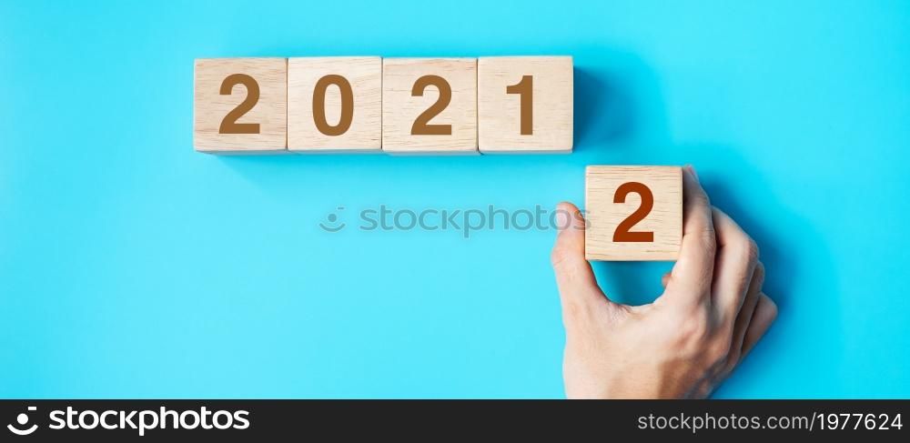 hand holding wooden cube block with 2022 text on blue background. Resolution, plan, review, goal, start and New Year holiday concepts