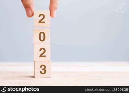 hand holding wooden cube block with 2023 text on table background. Resolution, plan, review, goal, start and New Year holiday concepts