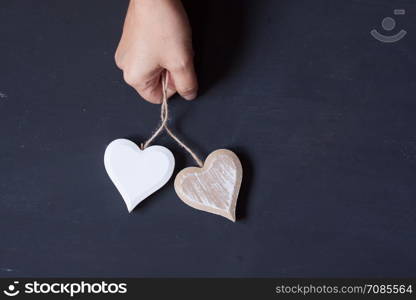 hand holding wooden hearts on a black background