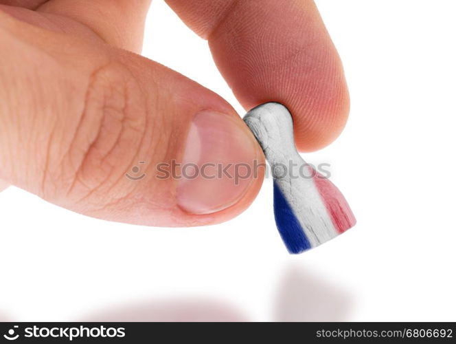 Hand holding wooden pawn with a flag painting, selective focus, France