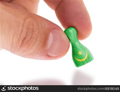 Hand holding wooden pawn with a flag painting, selective focus, Mauritania