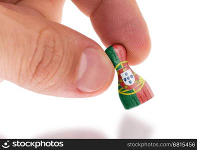 Hand holding wooden pawn with a flag painting, selective focus, Portugal