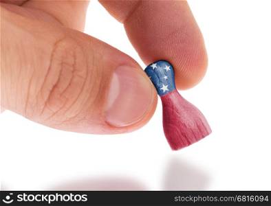 Hand holding wooden pawn with a flag painting, selective focus, Samoa