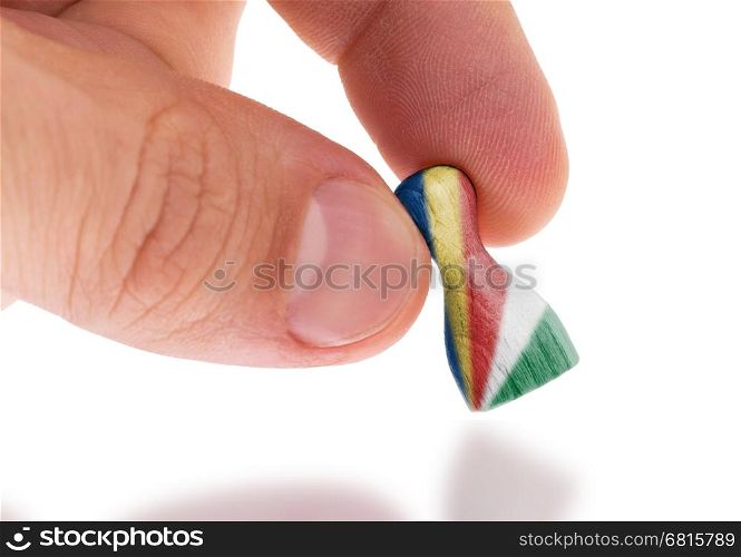 Hand holding wooden pawn with a flag painting, selective focus, the Seychelles