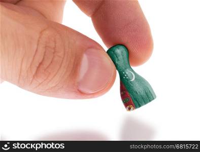 Hand holding wooden pawn with a flag painting, selective focus, Turkmenistan