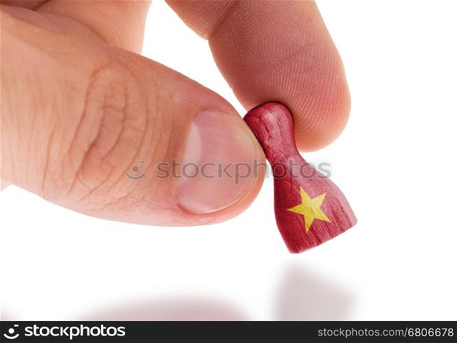 Hand holding wooden pawn with a flag painting, selective focus, Vietnam