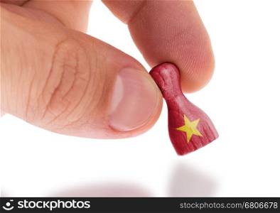 Hand holding wooden pawn with a flag painting, selective focus, Vietnam