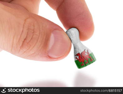 Hand holding wooden pawn with a flag painting, selective focus, Wales