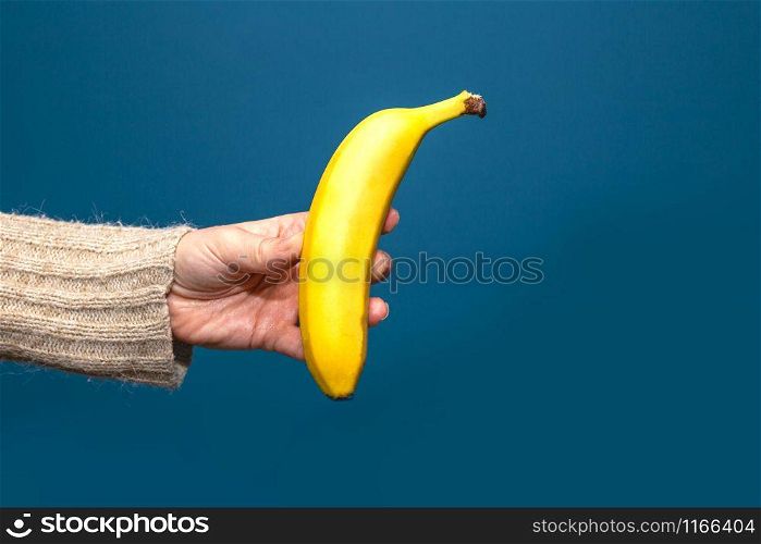 hand holding yellow banana fruit isolated on blue background. hand holding yellow banana fruit isolated near Blue background