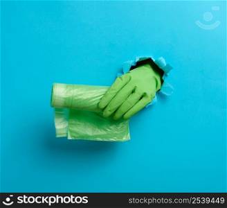 hand holds a bundle of transparent garbage bags on a blue background. A part of the body sticks out of a torn hole in the paper