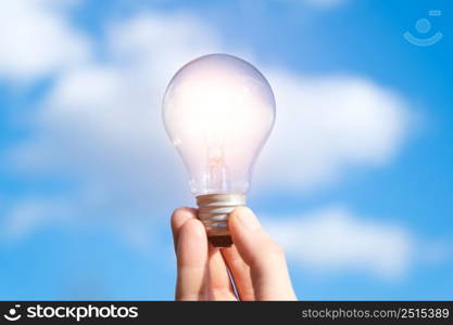 Hand holds a lamp on a background of blue sky and clouds. Concept of idea, startup, new opinion. A place to meditate or reboot.. Hand holds a lamp on a background of blue sky and clouds. Concept of idea, startup, new opinion. A place to meditate or reboot